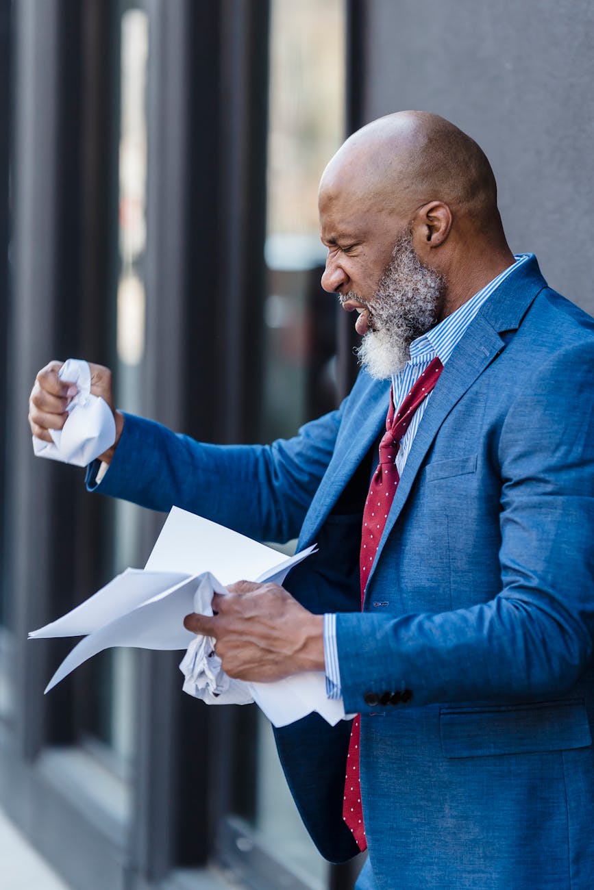 angry black businessman making crumpled paper on street