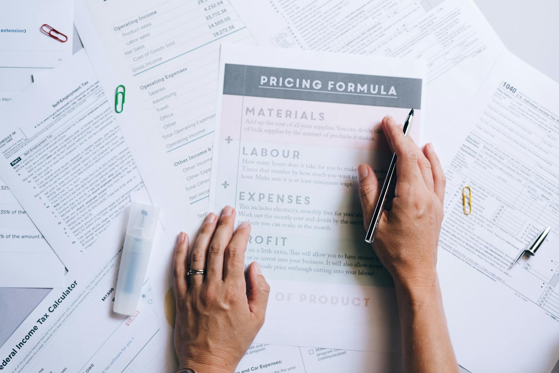 a person holding a pen while touching the documents on the table